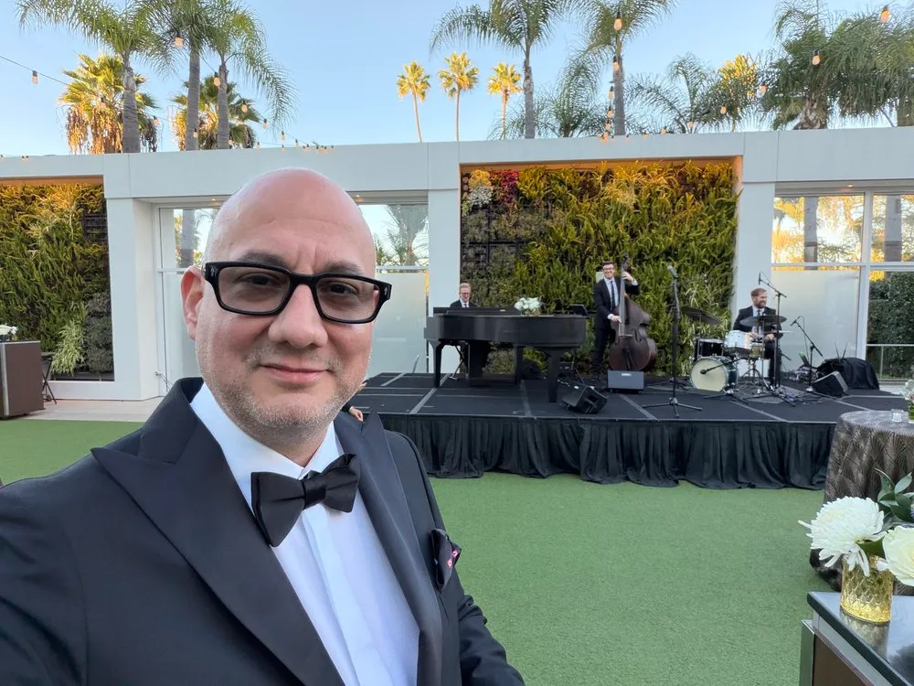 Luis Giraldo at the Beverly Hilton garden, in tuxedo, palm-lined backdrop
